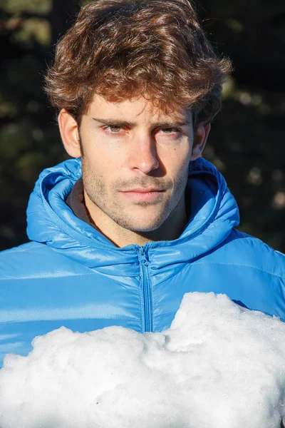 若い男が雪に覆われた冬の日 山に彼の手で大きな雪だるまを保持 — ストック写真