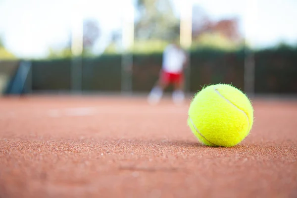 Tennis ball on the floor of a tennis court in a match in the shade.