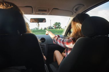 Genç kadın bir tatil gezisinde nereye işaret araba ön koltuklarda oturan. 