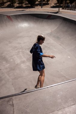 Genç kadın kentsel tarzı bir skatepark kaykay yapıyor ile. 