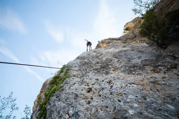 驚くほど晴れた日に山の壁を登る男性登山者のショットの下から — ストック写真