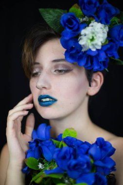 Şehvetli genç kadın yüzüne dokunmaktan ve uzakta ile mavi çiçek kompozisyon arıyorum  