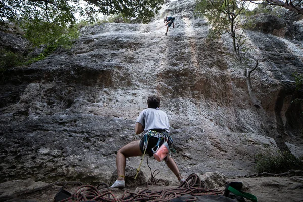 下ハーネスで匿名の人の山を見上げてチェック パートナーと登山の崖 — ストック写真