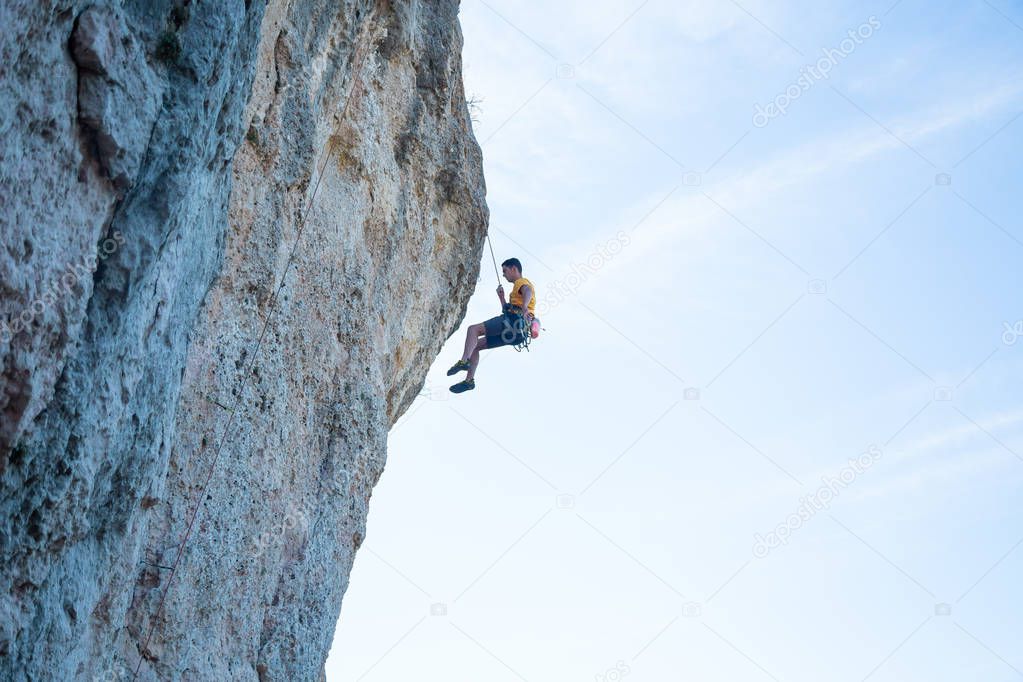 View of man without helmet hanging on a rope while rappelling and shows flying pirouettes in the air 