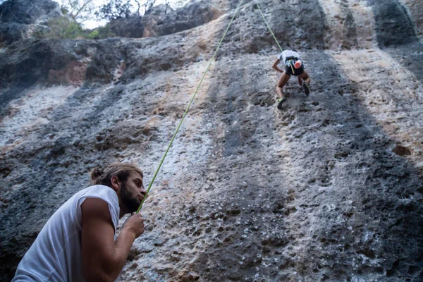 Man checking climber on mountain
