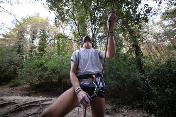 From below of man with rope on rock looking up checking another climber before going up