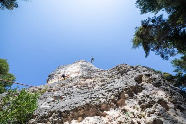 Dağcı atış aşağıdan iken diğer Tırmanma dağ mavi gökyüzü altında üstünden atlama ip ile güvenli