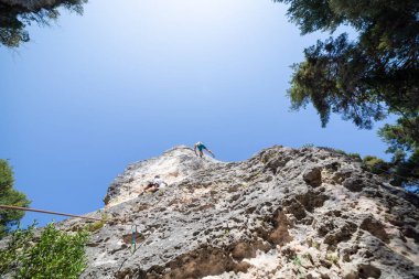Dağcı atış aşağıdan iken diğer Tırmanma dağ mavi gökyüzü altında üstünden atlama ip ile güvenli