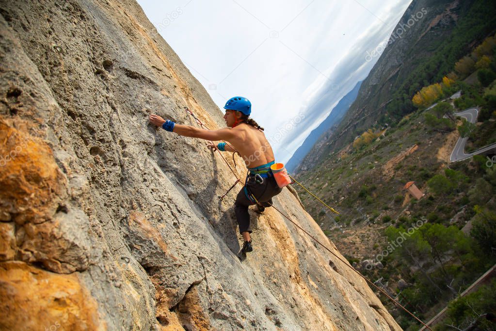 Shirtless climber man climbing mountain wall on amazing sunny day 