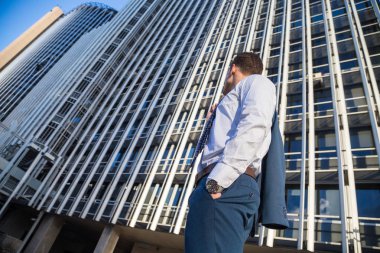 Şık takım elbise ceketi modern ofis gökdelen arka plan üzerinde tutan işadamı.