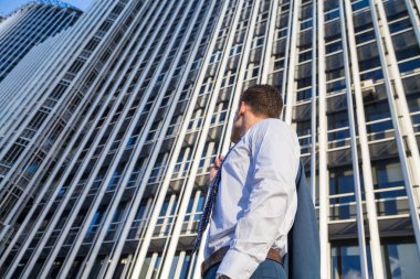 Şık takım elbise ceketi modern ofis gökdelen arka plan üzerinde tutan işadamı.