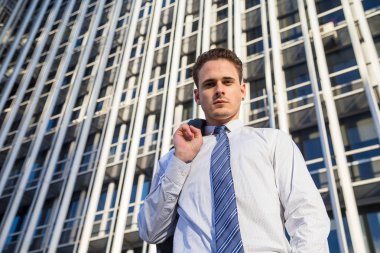 Şık takım elbise ceketi modern ofis gökdelen arka plan üzerinde tutan işadamı.