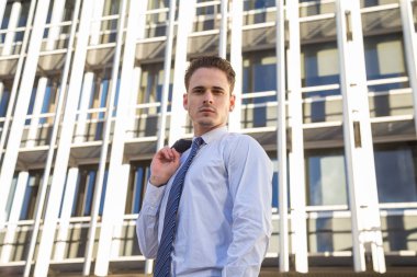 Şık takım elbise ceketi modern ofis gökdelen arka plan üzerinde tutan işadamı.