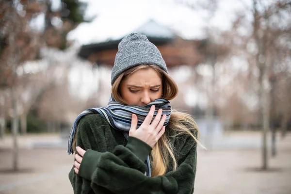 Eşarp kaydırma ve uzakta gerçekten soğuk günde Sonbahar Park arka plan bulanık üzerinde dururken seyir sıcak giysiler içinde genç ve güzel kadın 