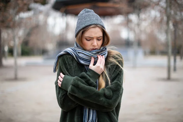 在非常寒冷的日子里 穿着温暖衣服的漂亮年轻女性穿着围巾包裹着 把目光移开 同时站在秋天公园模糊的背景上 — 图库照片