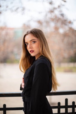 Bir çit oturan bir parkta poz güzel model kadın