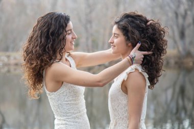 Sakin gölde gülümseyen ve sonbahar günü birbirlerine saç tarayan neşeli ikiz kız kardeşlerin yan görünümü