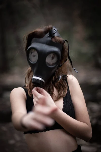 匿名妇女穿着黑色衣服和防毒面具站在惊人的恐怖森林的肖像 — 图库照片