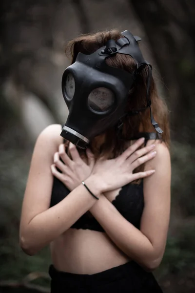 匿名妇女穿着黑色衣服和防毒面具站在惊人的恐怖森林的肖像 — 图库照片