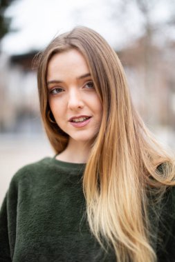 Sonbaharda bir parkta mutlu gülümseyen genç sarışın kadın Portresi