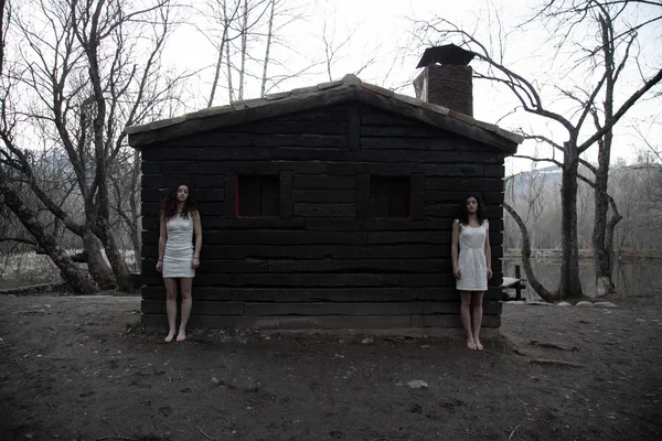 Young Twin Sisters White Dresses Standing Abandoned Wood House Mysterious — Stock Photo, Image