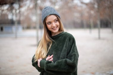 Sonbaharda bir parkta kış şapkalı mutlu gülümseyen genç sarışın kadın Portresi