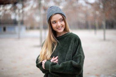 Sonbaharda bir parkta kış şapkalı mutlu gülümseyen genç sarışın kadın Portresi