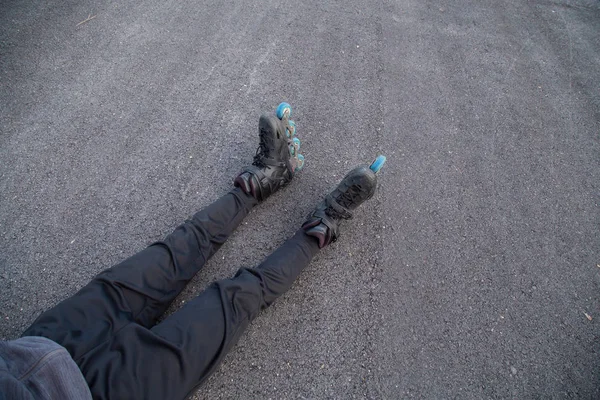 Legs of man with roller skates lying on road
