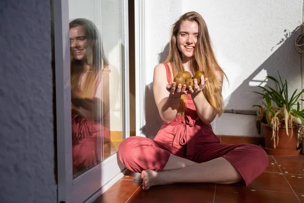 Jovem Fêmea Encantadora Vestido Verão Casual Sentado Varanda Oferecendo Kiwis — Fotografia de Stock