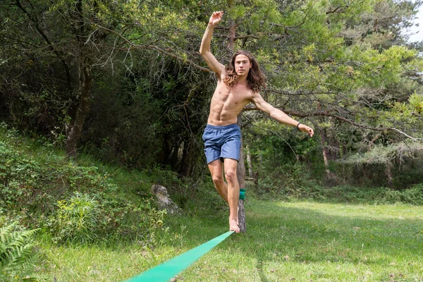 夏の緑のフィールドでスラックラインで裸の胴のバランスをとるアクティブな若者 — ストック写真