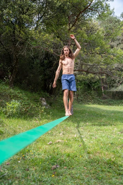 夏の緑のフィールドでスラックラインで裸の胴のバランスをとるアクティブな若者 — ストック写真