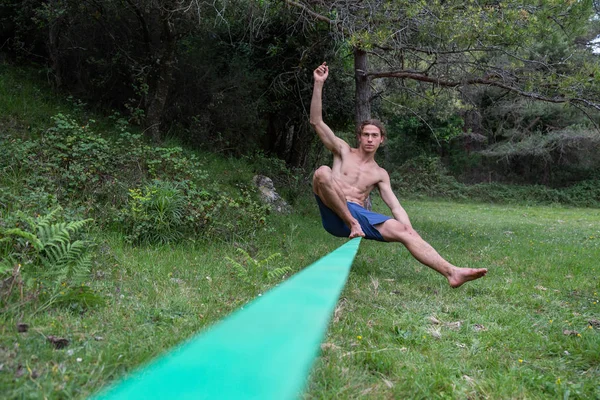 夏の緑のフィールドでスラックラインで裸の胴のバランスをとるアクティブな若者 — ストック写真