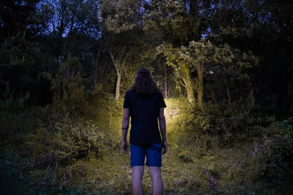 年轻人穿着短裤和T恤 夏天用头灯照亮森林的后视图 — 图库照片