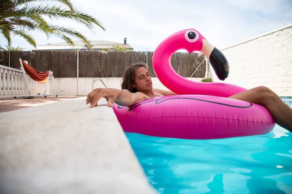 Ung Man Flyter Uppblåsbar Flamingo Blå Pool Solig Dag Sommarlov — Stockfoto