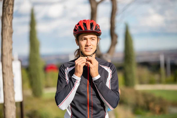 Güzel şehir parkında spor giyim burkulan koruyucu kask genç yakışıklı erkek bisikletçi 