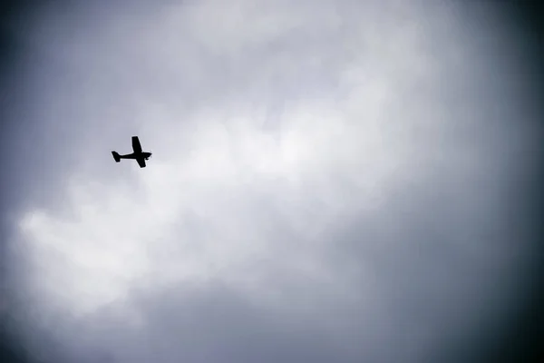 Pequeño avión silueta contra un cielo nublado . — Foto de Stock