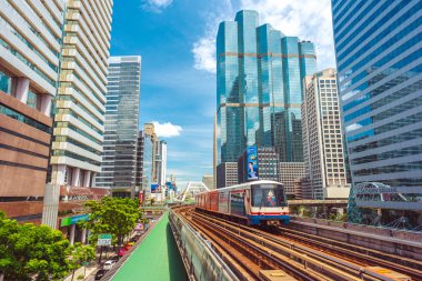 Bangkok - 9 Haziran 2019: BTS treni şehir merkezindeki gökdelenler arasında mavi gökyüzüne karşı ilerliyor. Bangkok Toplu Taşımacılık Sistemi günde 700 binden fazla kişiyi naklediyor.