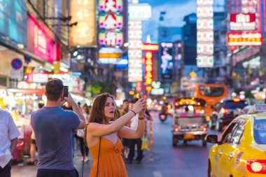 Bangkok, Tayland - 5 Haziran 2019: Taksiyle gelen iki hayran gezgin, gece vakti Çin Mahallesi Yaowarat Yolu 'nun güzelliğini cep telefonlarıyla çekiyorlar..
