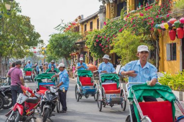 Hoi An, Vietnam - 28 Ekim 2018: Eski şehrin caddesi çekçekçekleri, sarı evleri, fenerleri, yemyeşil bitkileri ve çiçekleri ile.