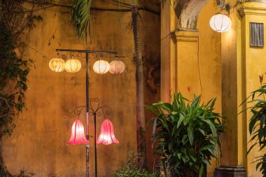  Eski kasabadaki eski püskü sarı duvar, kemer, fener ve saksıda bitki) geceleri. Hoi An, Vietnam
