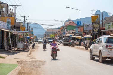 Vang Vieng, Laos - 28 Aralık 2018: Mütevazı trafik, sokak lambaları ve farklı turizm işletmelerini açıklayan tabelaları ile şehrin ana caddesi.