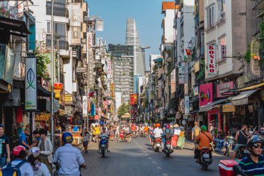 Ho Chi Minh City, Vietnam - January 7, 2019: Bui Vien Street crowded with people and road traffic with numerous signboards of hotels & restaurants and Bitexco Financial Tower at the end of perspective clipart