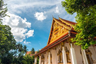 Wat Phra That Phoun (Wat That Foon), Vientiane City, Laos 'taki Budist tapınağı. Hindistan cevizi ağaçlarıyla yemyeşil bir bahçe ve güzel bulutlu mavi gökyüzü..