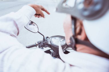 Motosiklet sürücüsü arkadan, yakın çekim, geniş açı. Beyaz kask, bir el, motosikletin gösterge paneli, dikiz aynası. Eski tarz filtre. Vietnam 'da motosiklet taksisiyle gidiyorum..