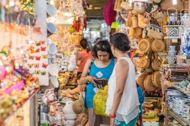 Ho Chi Minh City, Vietnam - 27 Nisan 2018: İki kadın gezgin Ben Thanh Market 'teki bir dükkandan hediyelik eşya alıyor, biri cüzdanındaki parayı kontrol ediyor. Ben Thanh Market ünlü bir Saigon turistik alışveriş merkezidir..