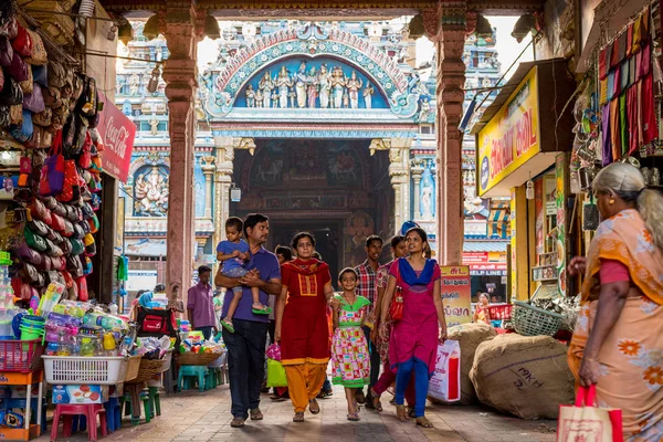 Madurai, Tamil Nadu / Hindistan - 14 Ocak 2016: Arkasında ünlü Meenakshi Tapınağı olan bir Hint ailesi dükkanların bulunduğu kemerden geçiyor. Tapınak şehrin en önemli turistik yeridir..