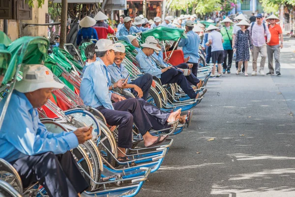 Hoi An, Vietnam - 23 Ekim 2018: Üniformalı uzun bir sıra müşteri bekliyor, konik şapkalı bir grup turist (arka planda bulanık) olay yerine yaklaşıyor.