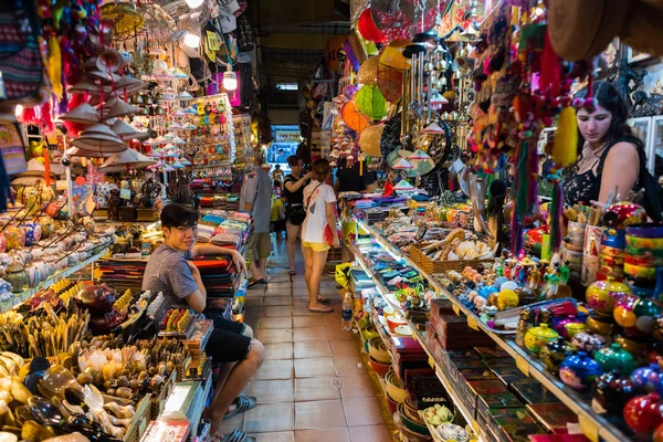Ho Chi Minh, Vietnam - 30 Nisan 2018: Ben Thanh Market 'in çeşitli hediyelik eşyalar ve bir satıcı arasında geçişi, gülümseyen genç Asyalı bir adam. Burası turistler için ünlü bir alışveriş merkezi..