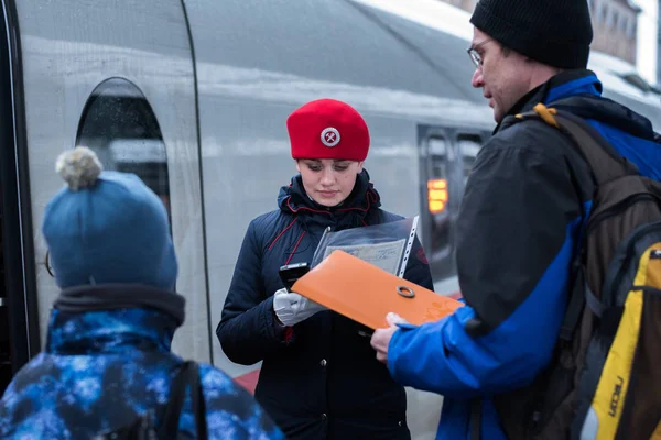 Saint Petersburg, Rusya - 29 Ekim 2017: Sapsan ekspres tren kırmızı bereli bir kondüktör Moskovsky tren istasyonunda çocuklu bir yolcuyu elektronik cihaz kullanarak kontrol ediyor..