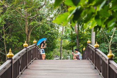 Bangkok, Tayland - 16 Aralık 2017: Sri Nakhon Khuean Khan Park 'ta ve Bang Krachao' da (Kachao) Botanik Bahçesinde şemsiyeli gülümseyen Asyalı genç kadının fotoğrafları).